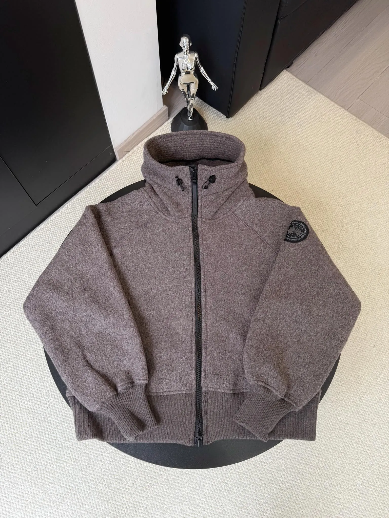P660 Canada Goose Fleece Wool Hooded Jacket Fabric selection: Wool fleece fabric blended with wool as the main body and a very small amount of spandex and polyester fiber. Wool is a core natural ingredient that provides unparalleled temperature regulation, antibacterial and anti-odor properties and a skin-friendly feel. The feeding of a small amount of spandex gives the fabric a certain degree of four-way elasticity, making it non-restrictive during daily activities. As the basis of fleece's structure, polyester fiber enhances the fabric's durability, wrinkle resistance and quick-drying properties. It contributes to the loft of the fleece and provides functions such as trapping air.  Detail 1: The sleeves and hem are closed with 2×2 ribbing. Its strong elasticity can closely fit wrists and waists of different thicknesses, forming an effective 'seal' to prevent cold wind from blowing back. It can still maintain its original shape after repeated stretching and use, and is not easy to loose and deform. And the ribbed cuffs can convey a sense of design and enhance the visual beauty.  Detail 2: The combination of hood design and elastic buckle improves warmth and windproof performance when wearing. Accessories: Customized elastic drawstring, elastic buckle, custom zipper pendant, custom armband Size: S M L Color: black gray coffee rice pink